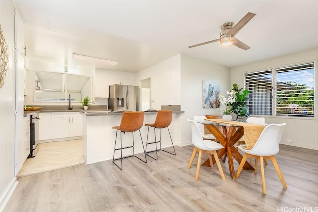 dining space featuring ceiling fan and light wood-type flooring