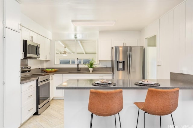 kitchen featuring stainless steel appliances, a breakfast bar, and white cabinets