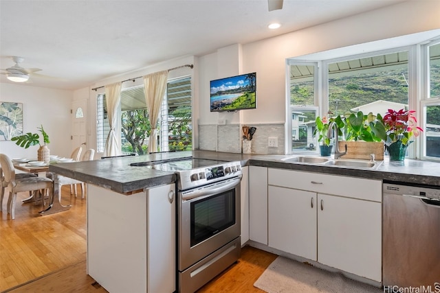 kitchen with sink, light hardwood / wood-style flooring, appliances with stainless steel finishes, white cabinetry, and kitchen peninsula