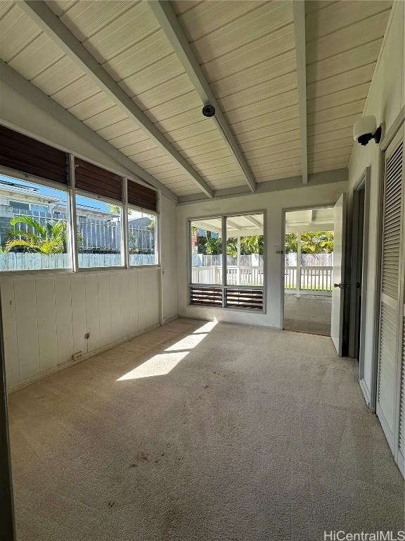 unfurnished sunroom with vaulted ceiling with beams