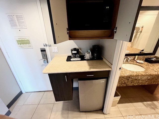 kitchen with dark brown cabinets, sink, and light tile patterned floors