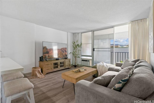 living room featuring a wall of windows, light wood-type flooring, cooling unit, and a textured ceiling