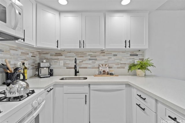 kitchen featuring white appliances, white cabinets, and a sink