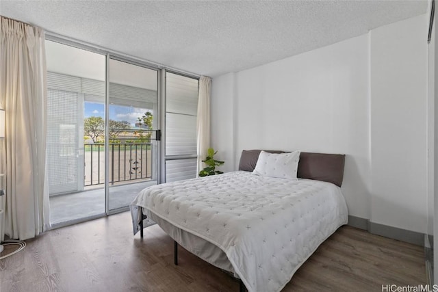 bedroom featuring a wall of windows, access to exterior, a textured ceiling, and wood finished floors