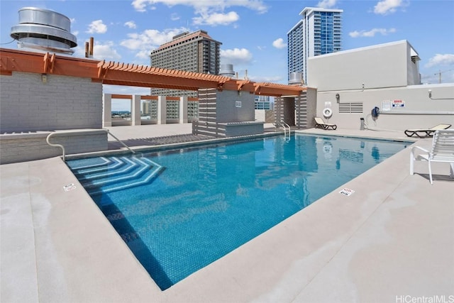 community pool with a patio area, a city view, and a pergola