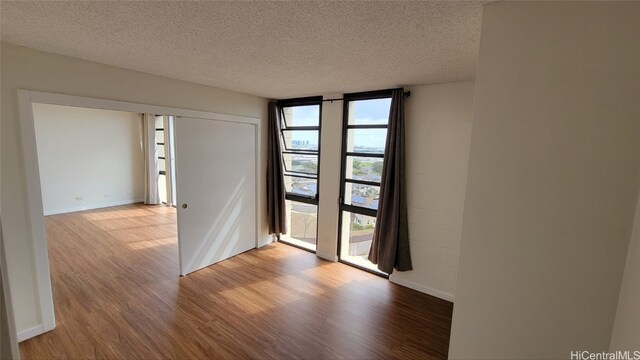 unfurnished room featuring hardwood / wood-style flooring, expansive windows, and a textured ceiling