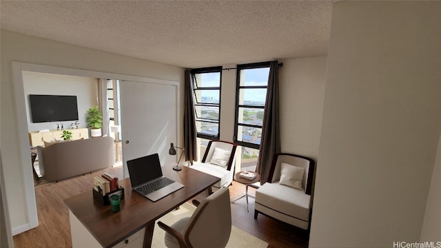 home office featuring wood-type flooring, expansive windows, and a textured ceiling