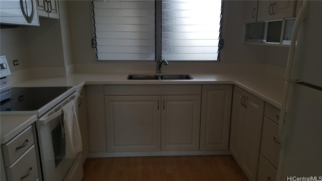 kitchen featuring hardwood / wood-style flooring, white appliances, white cabinetry, and sink