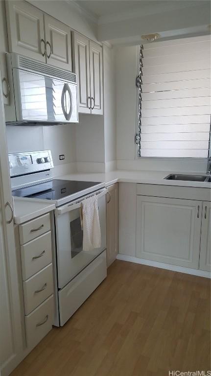 kitchen featuring white cabinetry, sink, white appliances, and light hardwood / wood-style flooring