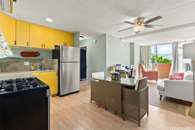 kitchen with sink, light hardwood / wood-style flooring, stainless steel refrigerator, decorative backsplash, and range with gas cooktop