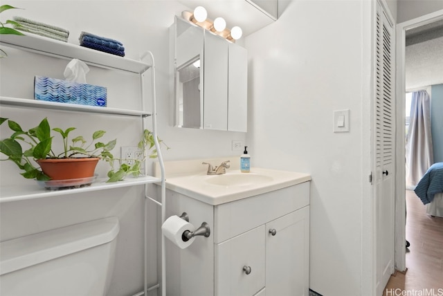 bathroom with vanity, toilet, and hardwood / wood-style floors