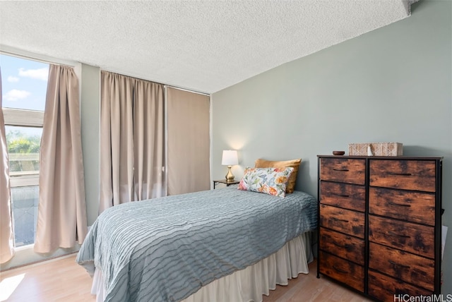 bedroom with a textured ceiling and light hardwood / wood-style flooring