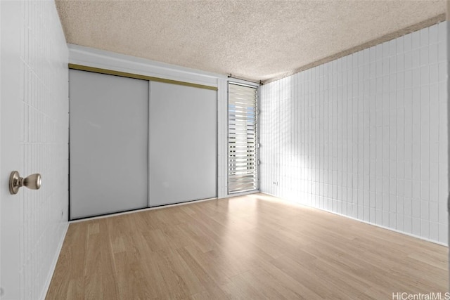 unfurnished bedroom with light hardwood / wood-style floors, a closet, and a textured ceiling