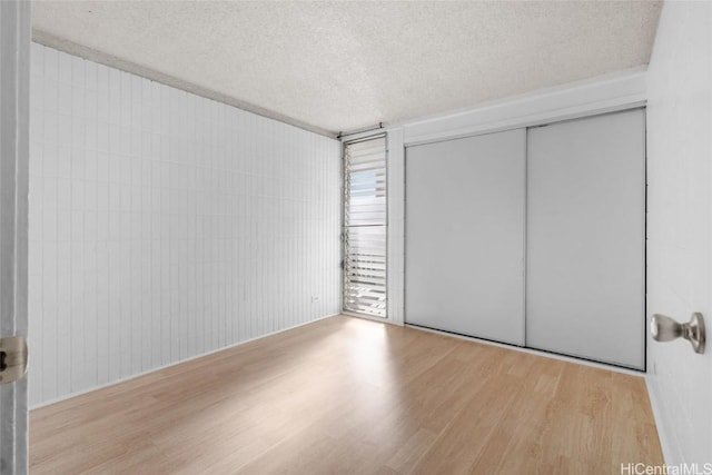 unfurnished bedroom with light hardwood / wood-style floors, a closet, and a textured ceiling