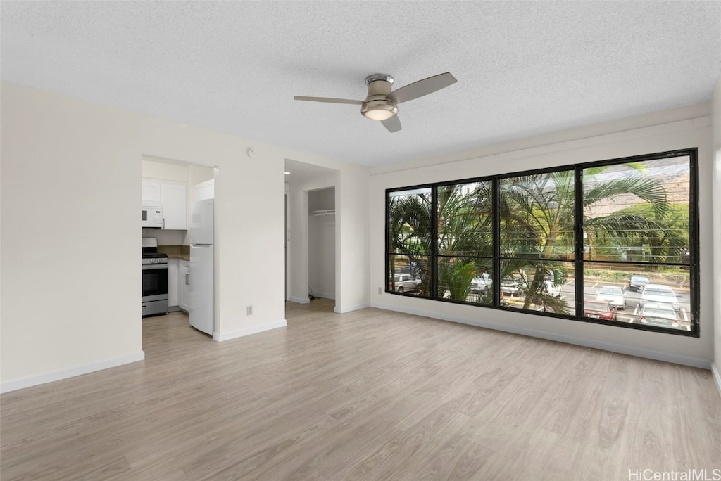 unfurnished living room with ceiling fan, light hardwood / wood-style floors, and a textured ceiling