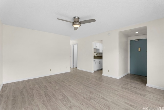 unfurnished living room with sink, a textured ceiling, ceiling fan, and light wood-type flooring