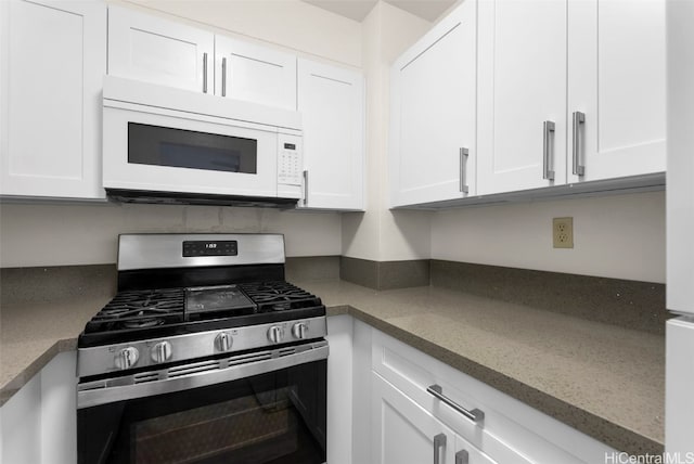 kitchen with gas range, white cabinets, and light stone counters