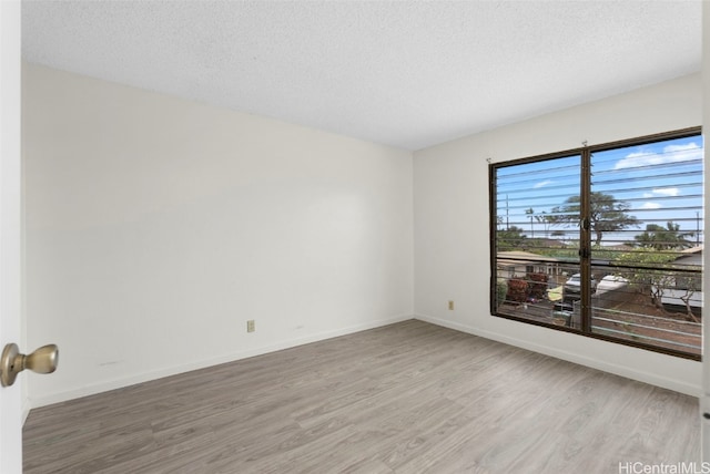 empty room with wood-type flooring and a textured ceiling