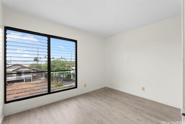 empty room with a textured ceiling and light wood-type flooring