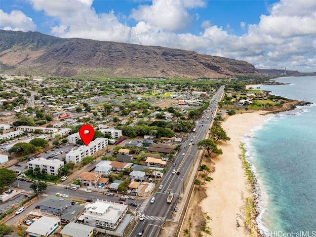 drone / aerial view with a water and mountain view and a beach view