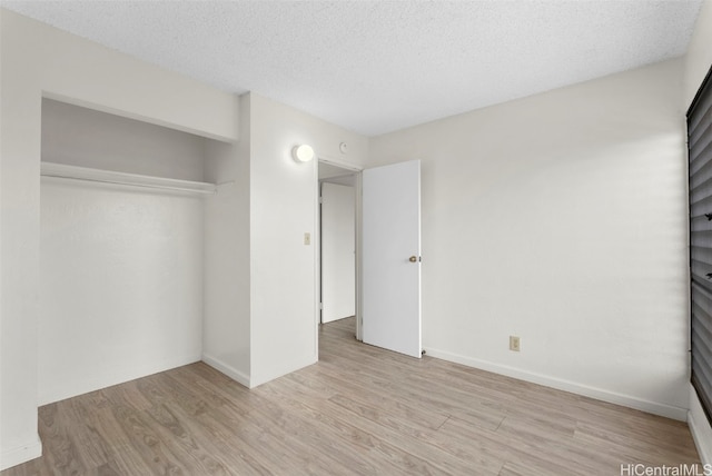 unfurnished bedroom featuring light wood-type flooring, a textured ceiling, and a closet