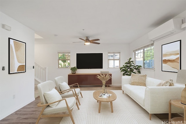 living room with light hardwood / wood-style floors, an AC wall unit, and ceiling fan