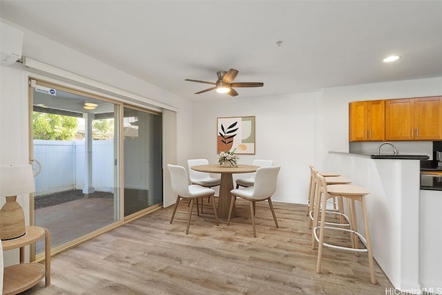 dining space featuring ceiling fan, a wall unit AC, and light wood-type flooring