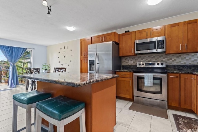 kitchen with backsplash, stainless steel appliances, a breakfast bar, and a center island