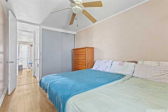 bedroom with a textured ceiling, light hardwood / wood-style flooring, and ceiling fan