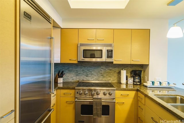 kitchen featuring high end appliances, sink, tasteful backsplash, and light brown cabinets