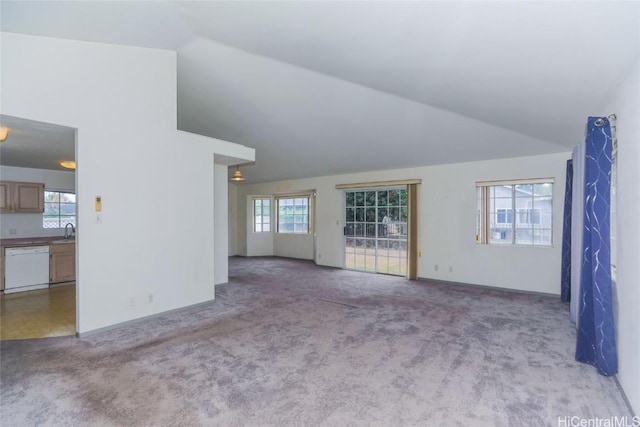 unfurnished living room featuring light carpet, sink, and vaulted ceiling