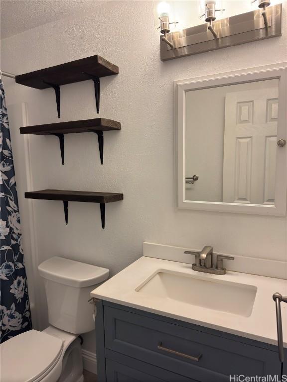 bathroom with walk in shower, vanity, and toilet