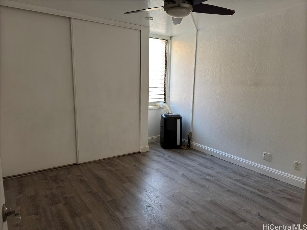 unfurnished bedroom featuring dark wood-type flooring and ceiling fan