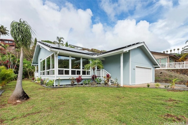 back of property featuring a yard, a garage, a sunroom, and solar panels