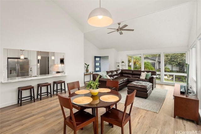 dining room featuring ceiling fan, high vaulted ceiling, light hardwood / wood-style floors, and sink