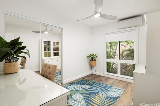 office space featuring ceiling fan, light hardwood / wood-style floors, and a wall mounted AC