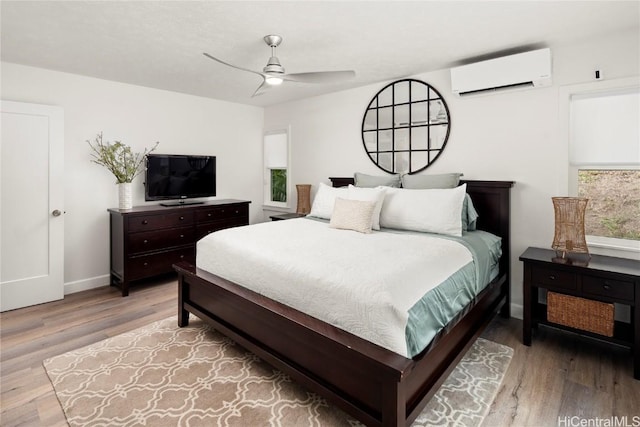 bedroom featuring ceiling fan, a wall unit AC, and light hardwood / wood-style floors