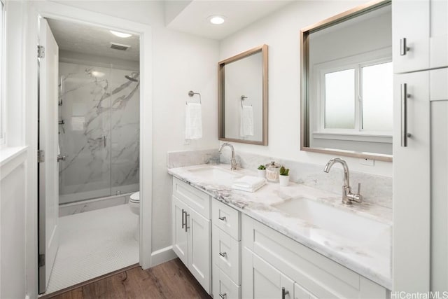 bathroom featuring wood-type flooring, vanity, an enclosed shower, and toilet