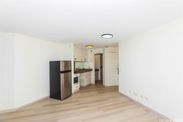 unfurnished living room featuring sink and light wood-type flooring