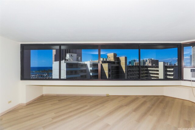 empty room with a city view, wood finished floors, and baseboards