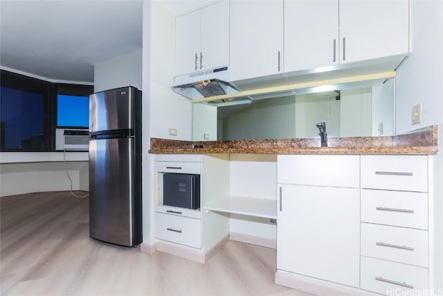 kitchen with sink, stainless steel fridge, dark stone counters, light hardwood / wood-style floors, and white cabinets