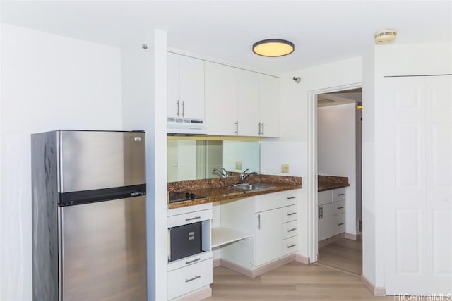 kitchen with white cabinetry, sink, stainless steel fridge, and light hardwood / wood-style flooring