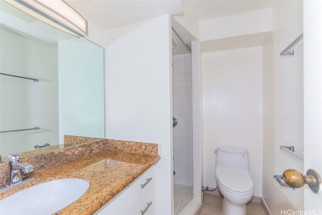 bathroom with vanity, tiled shower, and toilet