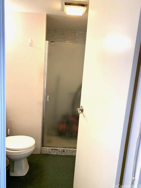 bathroom with a shower with shower door and toilet