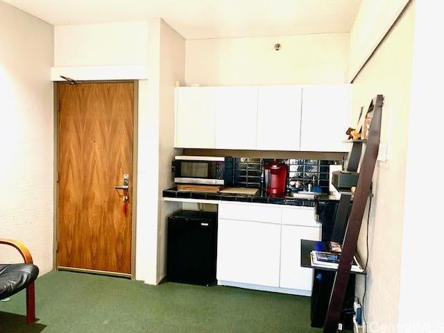 kitchen featuring white cabinetry, tile counters, and refrigerator