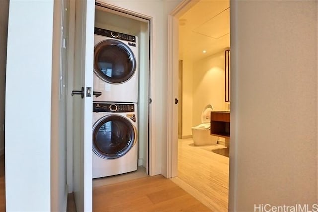 clothes washing area with stacked washer and clothes dryer and light hardwood / wood-style flooring