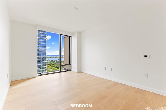 spare room featuring light wood finished floors and baseboards