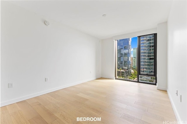 spare room featuring light wood-style flooring, baseboards, and a city view