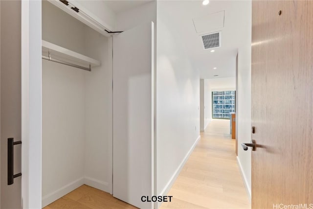 corridor featuring light wood-style flooring, visible vents, and baseboards