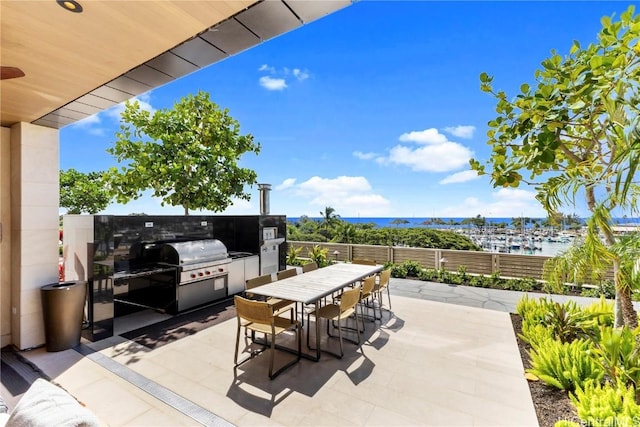 view of patio featuring a water view, fence, a bar, and area for grilling